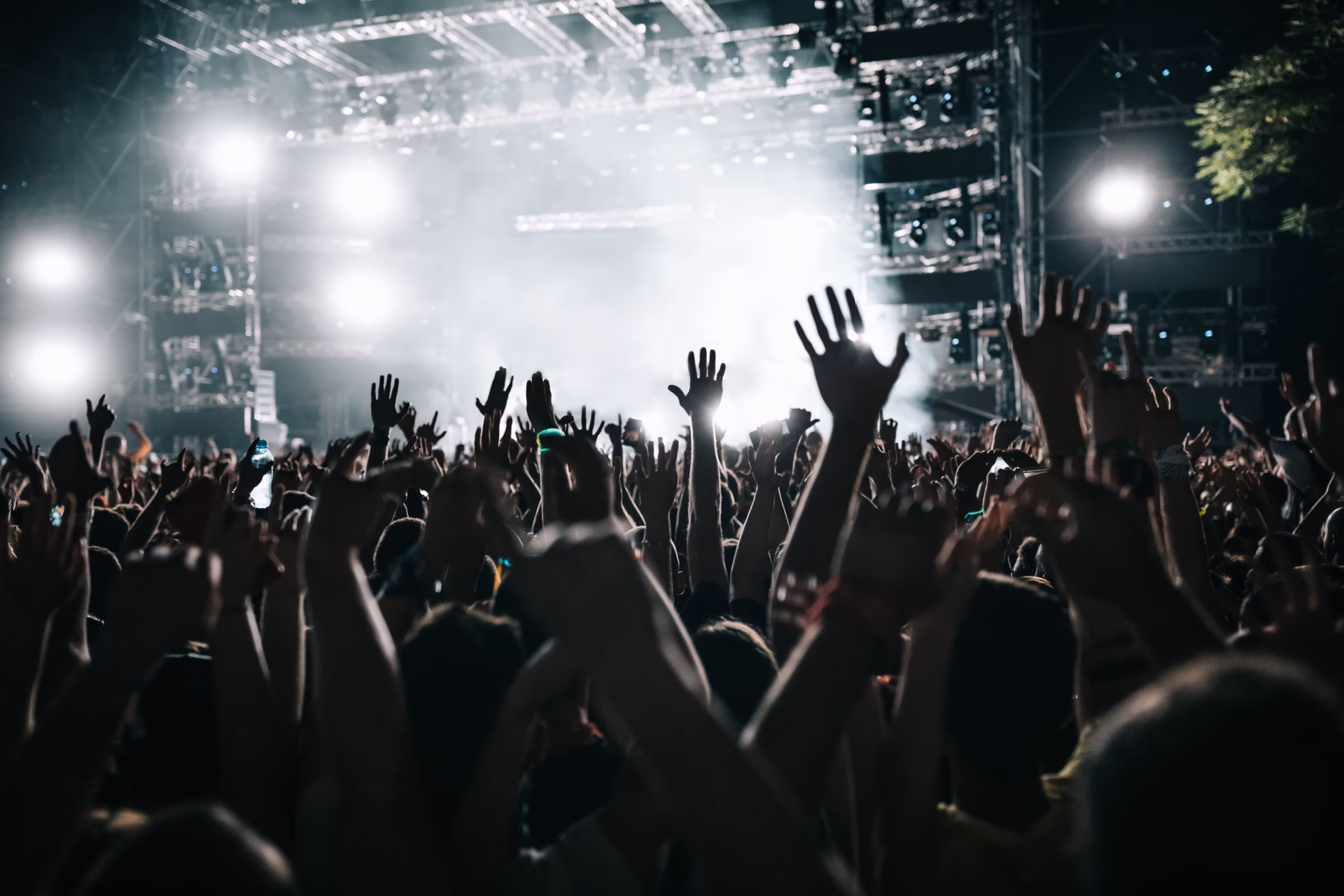 Crowd with raised hands in front of a lit festival stage