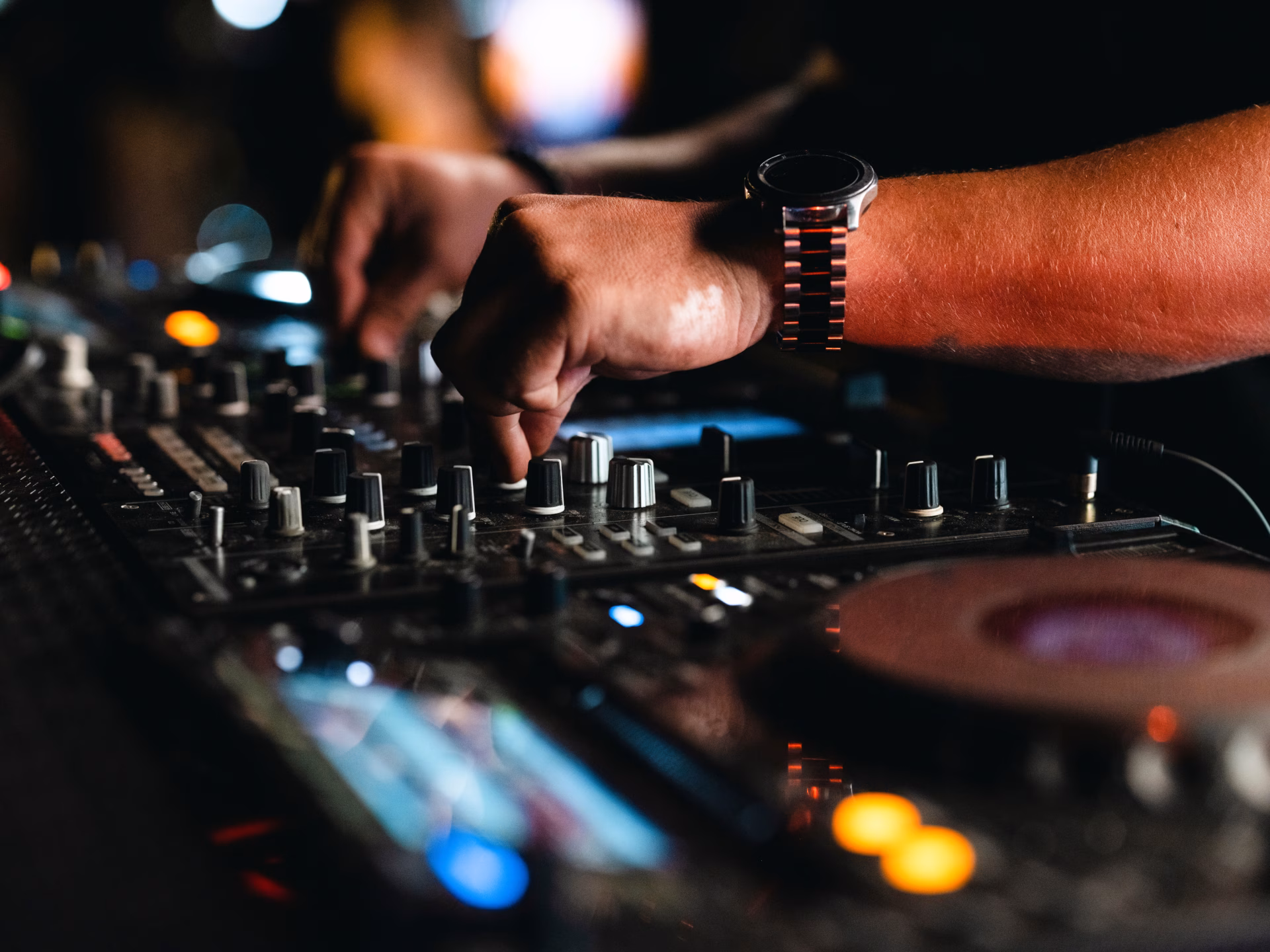 DJ hands working a mixer and turntable