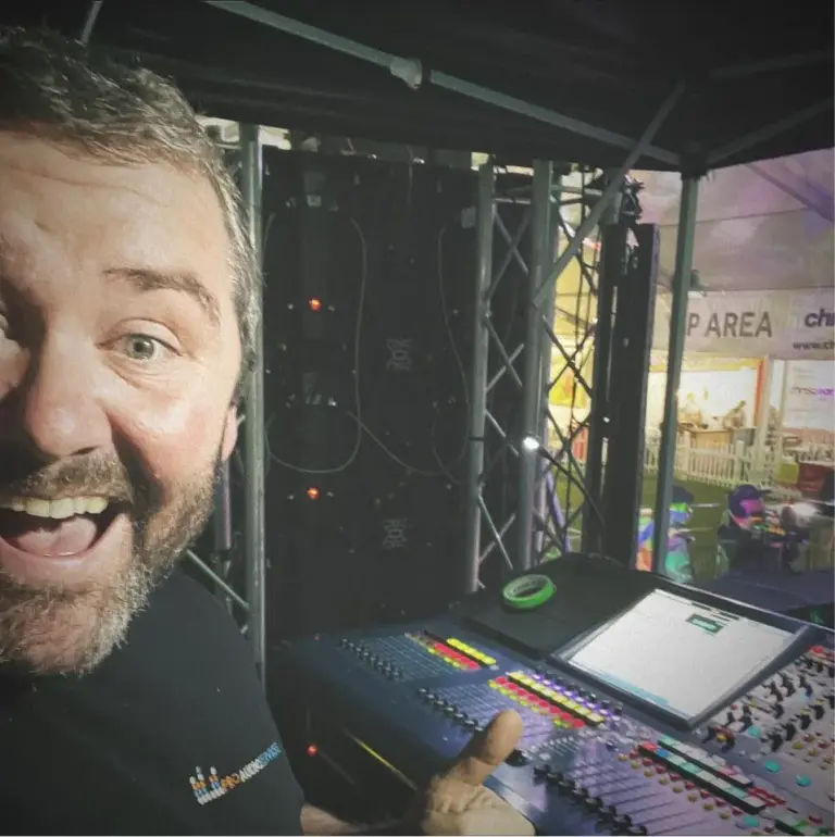 Ben Jones smiling beside racked equipment and a mixing desk