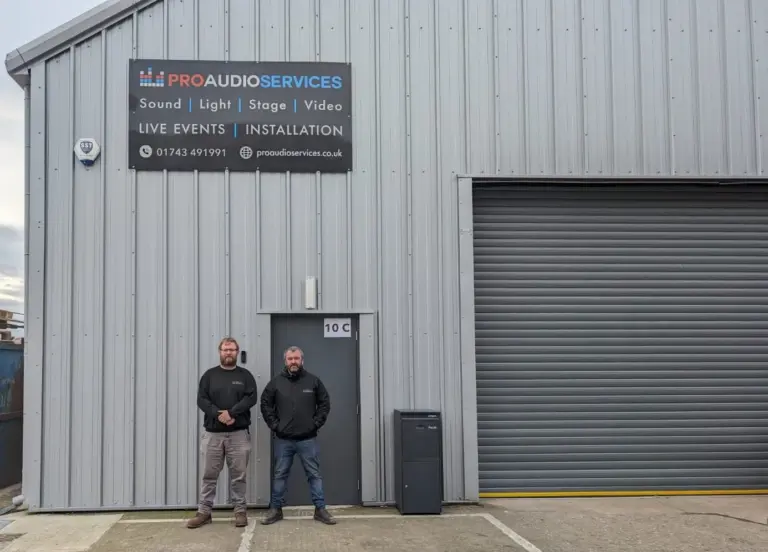 Two men standing outside the Pro Audio Services unit under the company sign