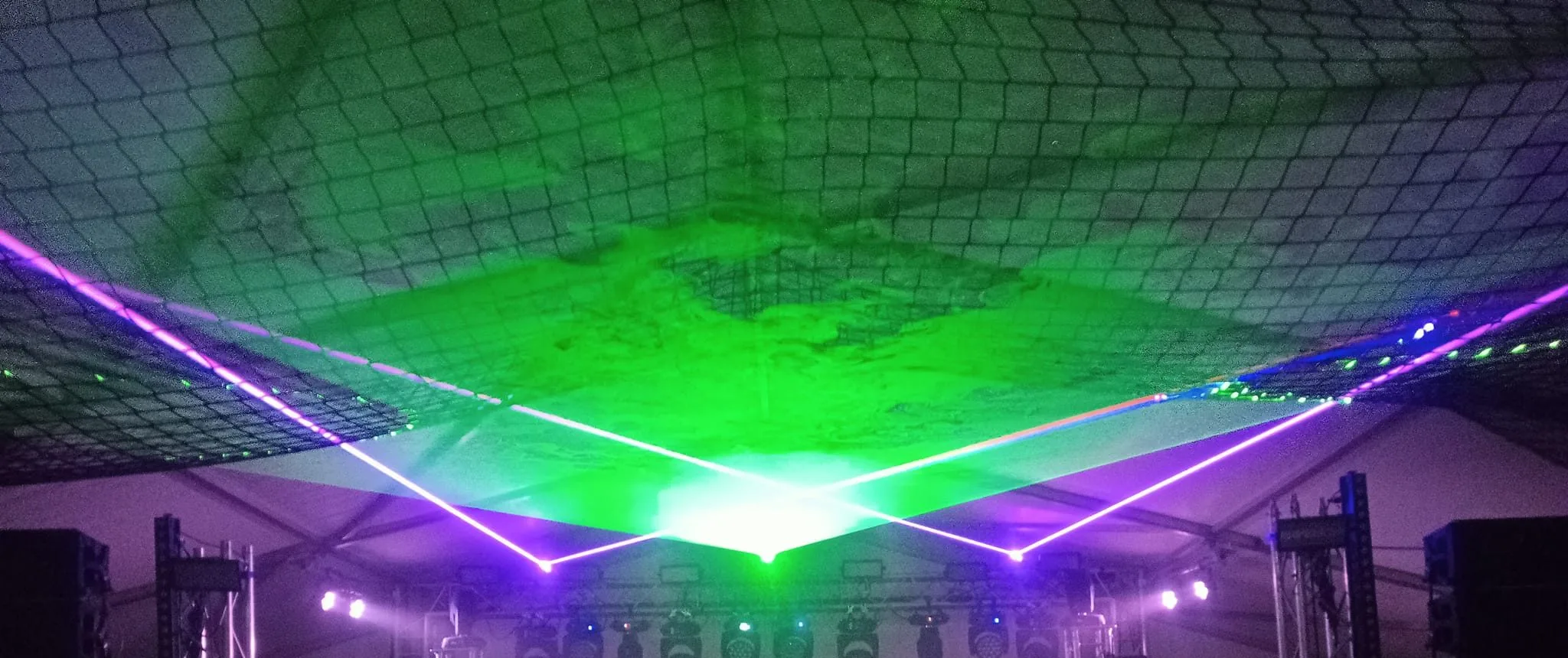 Green laser display with purple light lines over a venue floor
