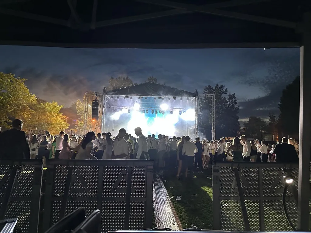 Festival stage with a large LED screen glowing at night and a crowd in front