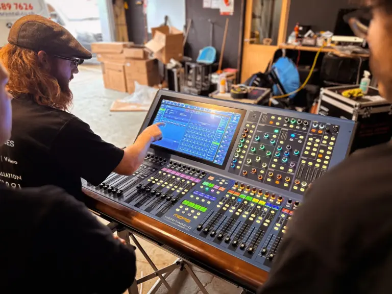 Engineer in a cap and headset operating a digital mixing console touchscreen