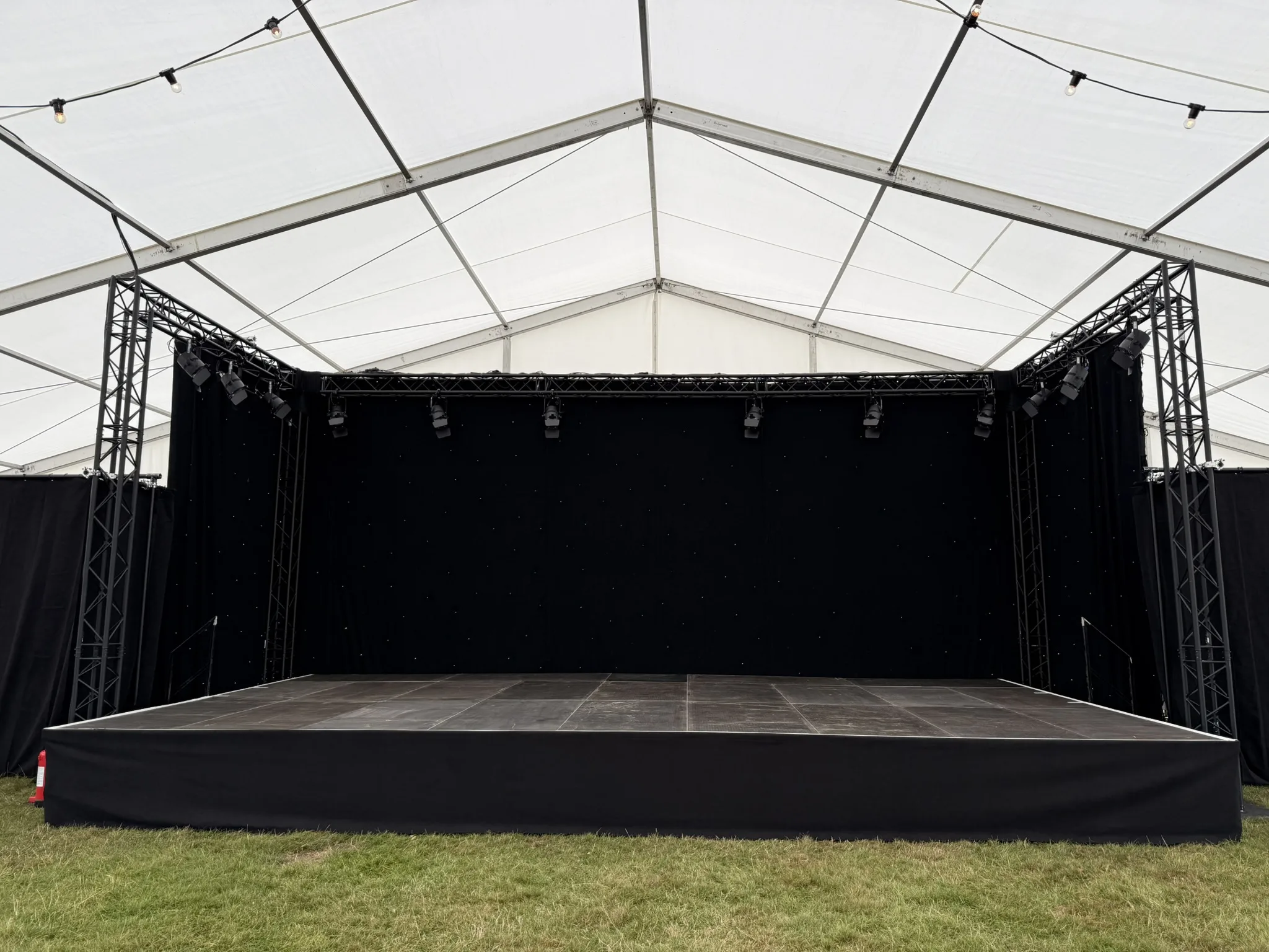 Front view of a low, large stage platform within a large marquee