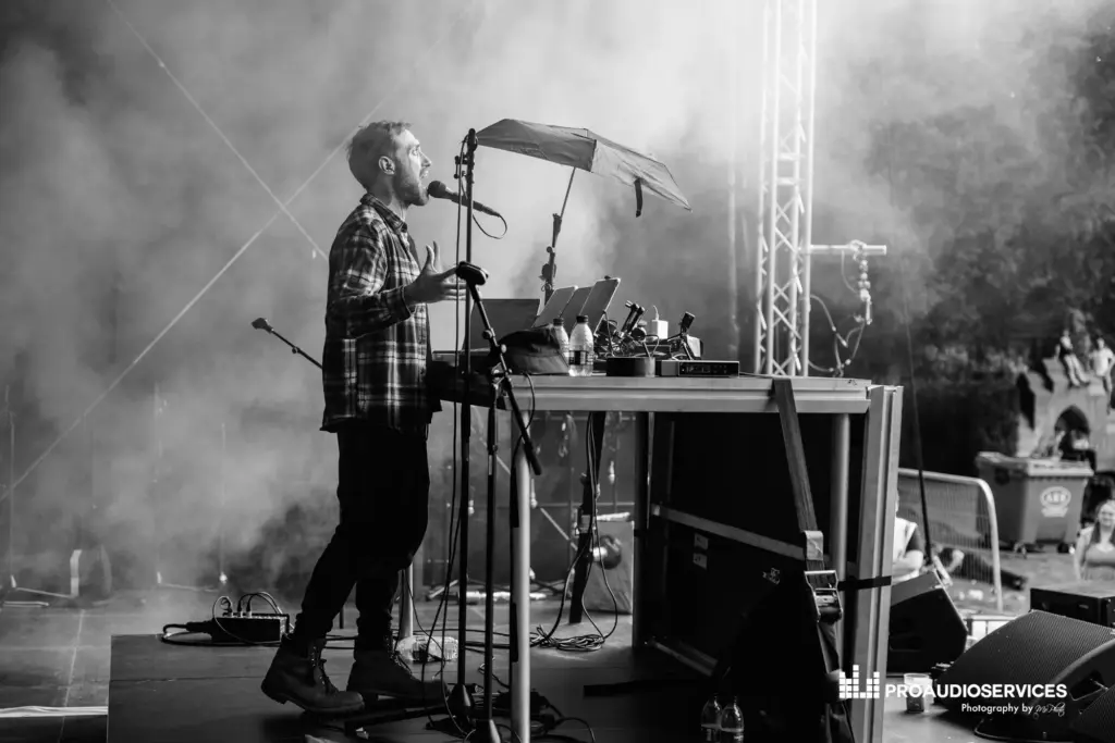 Black and white shot of two musicians playing on stage, with keyboards and a microphone stand