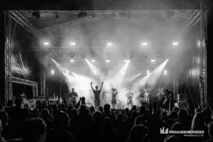 Dutty Moonshine band performing on a stage with lights eluminating them from behind