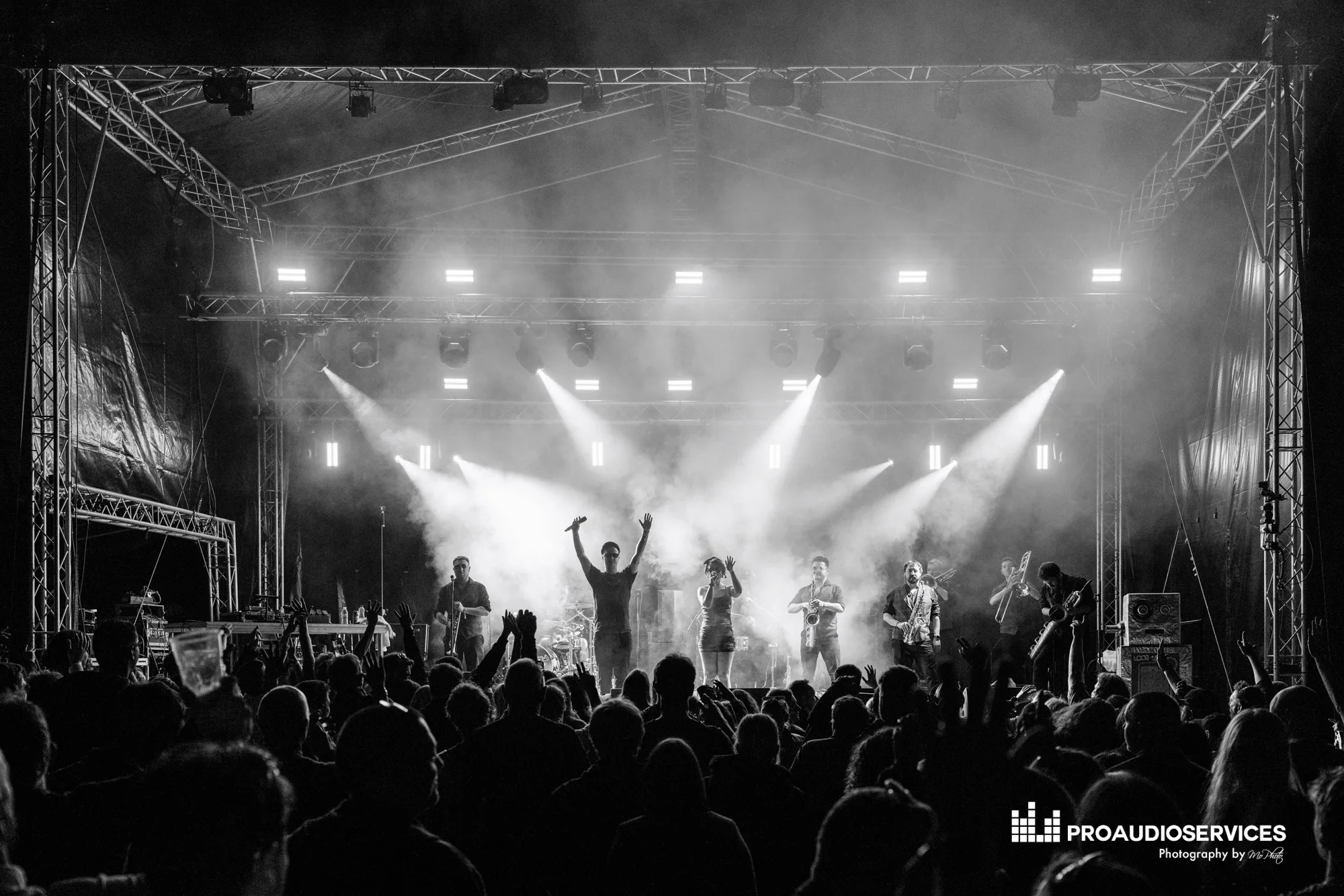 Dutty Moonshine band performing on a stage with lights eluminating them from behind