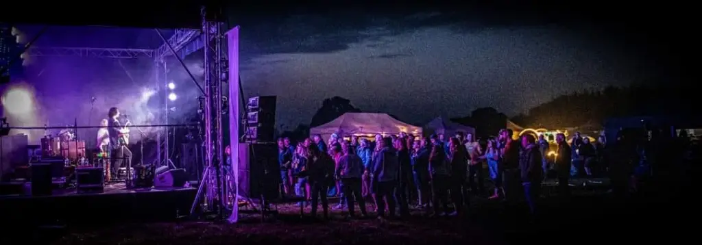 Wide night shot of a stage lit up on a field at Meadowfest