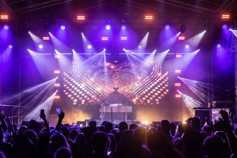 Crowd with raised hands in front of a purple and white lighting rig at Woodshrop 2025 in Shrewsbury, produced by Pro Audio Services