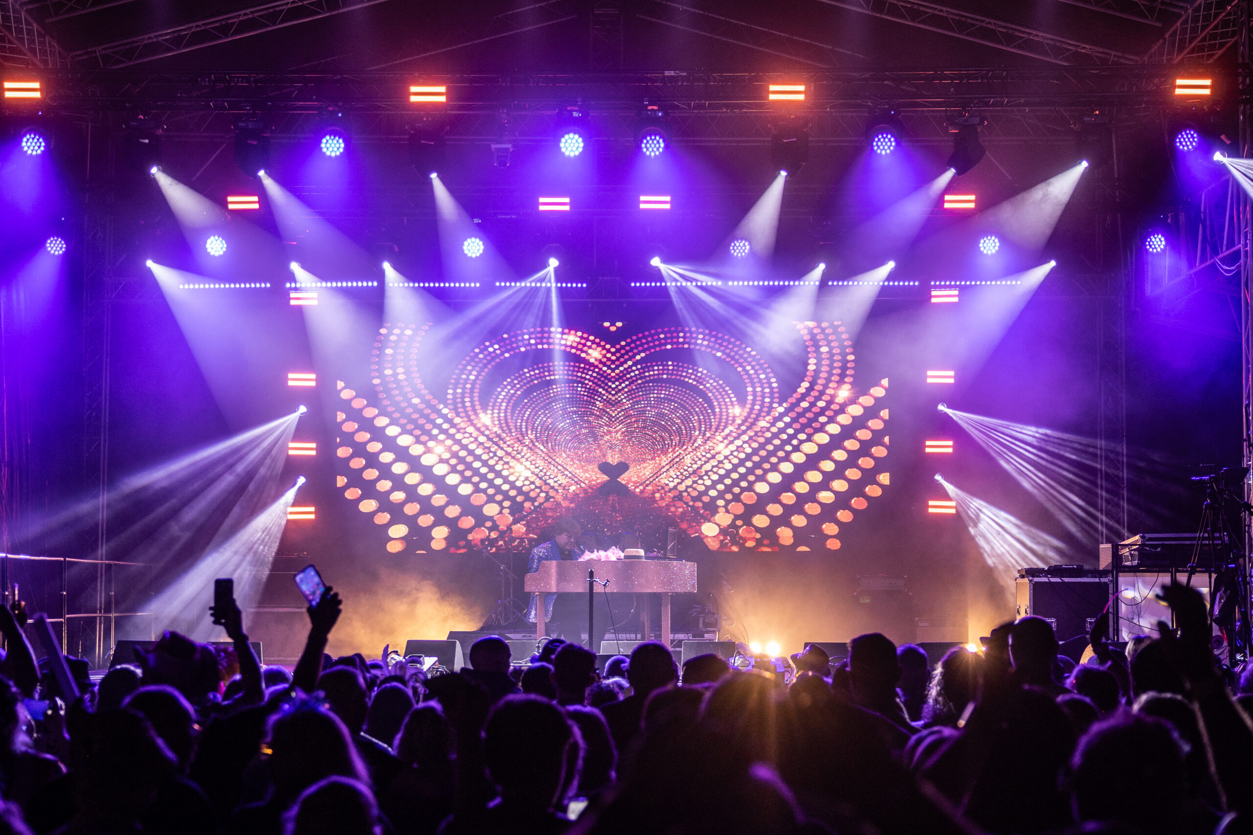 Crowd with raised hands in front of a purple and white lighting rig at Woodshrop 2025 in Shrewsbury, produced by Pro Audio Services