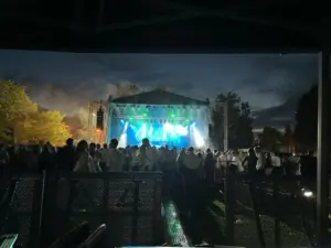 Large stage outside at night with video wall at the back and lights shinning out over the adience in front.