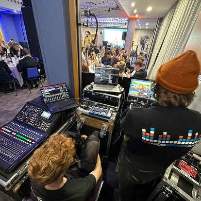 Engineer at a digital mixing desk behind the stage at a charity gala dinner