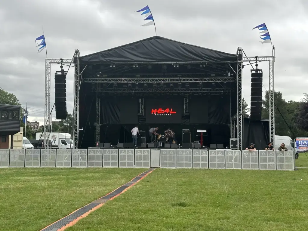 Black-canopied stage in a field with speaker stacks and flags at Heal Festival before the crowd arrives