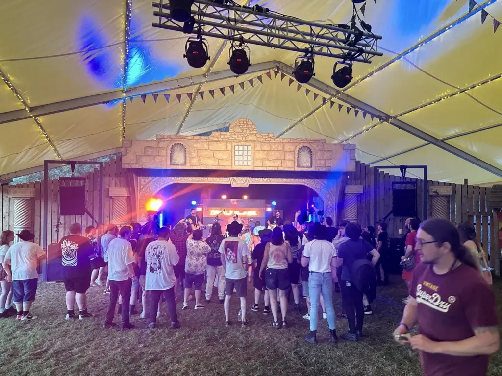 Marquee stage with lighting rig and a crowd of festival-goers in front