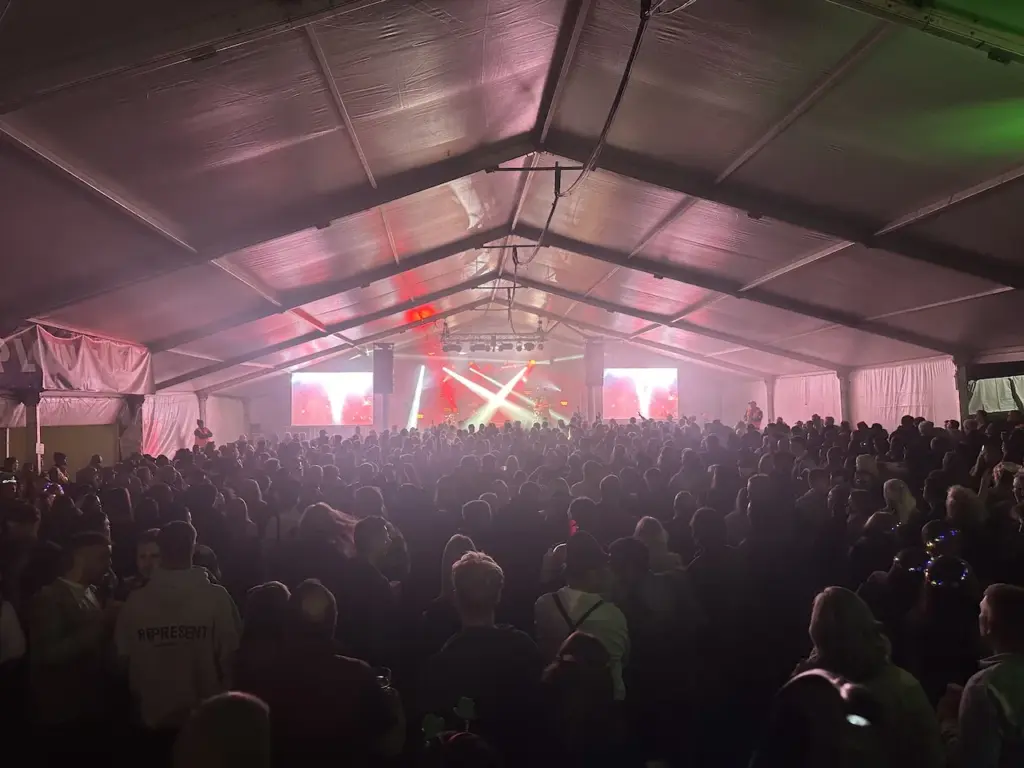 Marquee interior with pink and purple lighting above the crowd