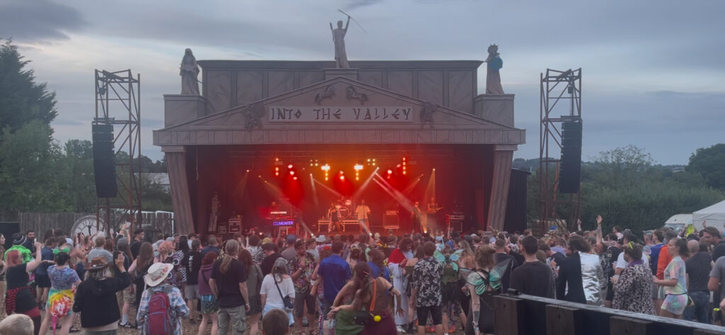Festival stage with a red-lit backdrop and the crowd in the foreground at Nozstock