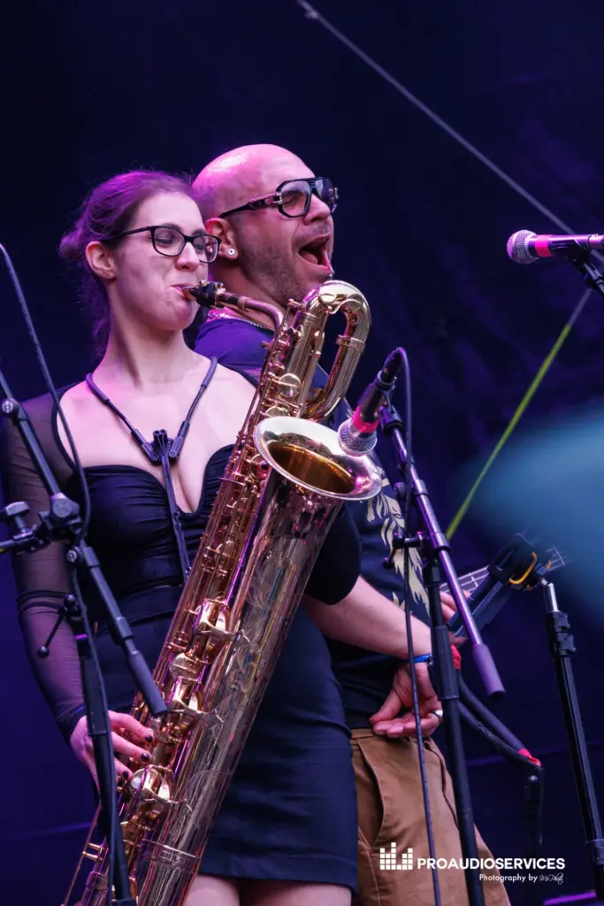 Saxophonist and singer performing on stage with stage lights behind them