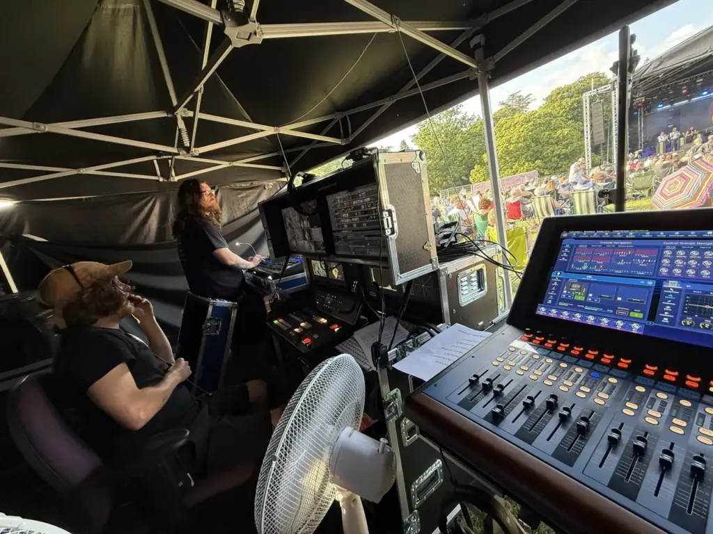 Digital mixing desk under a gazebo with a technician working behind it