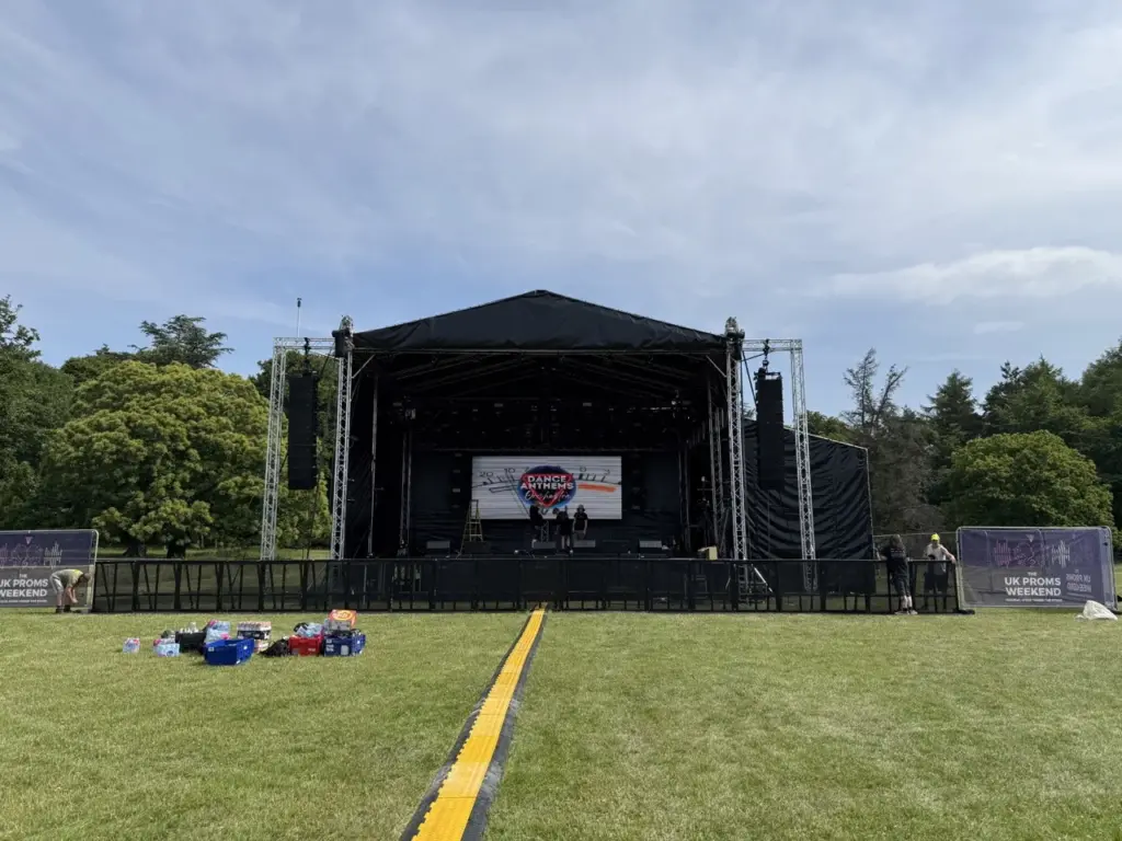 Empty field with a black-canopied stage and speaker towers before the audience arrives