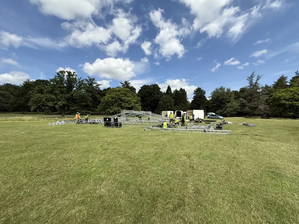 Open parkland with stage equipment in the distance under a blue sky