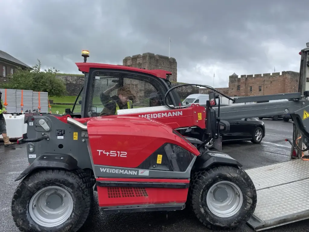 Red telehandler parked on site beside the castle walls during the build in Carlisle