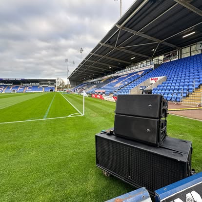 Line array speakers set up beside the pitch in an empty football stadium