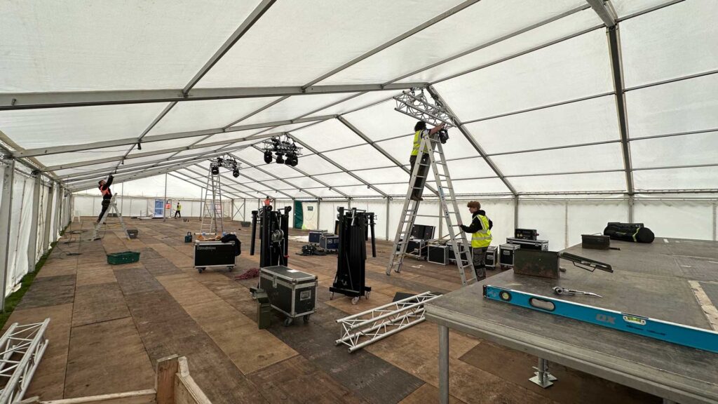 Large empty marquee with a stage and equipment being set up ready for the ball