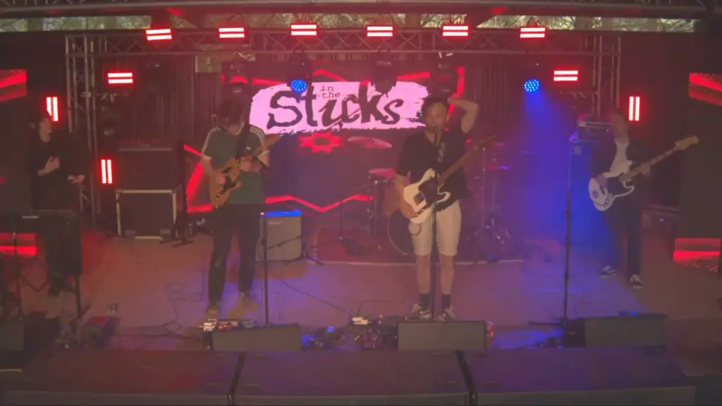 Band performing on stage with video wall behind them