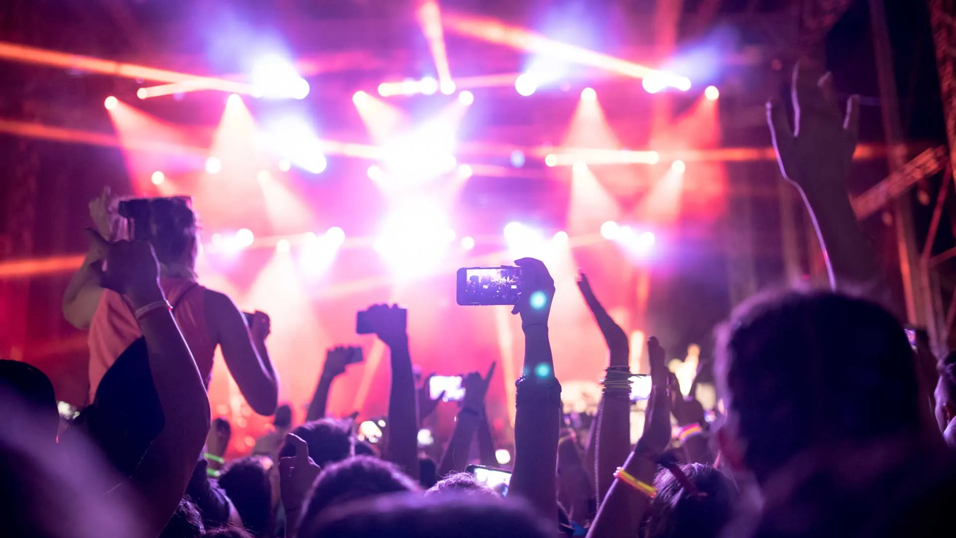 Crowd in front of stage lighting rig with hands up