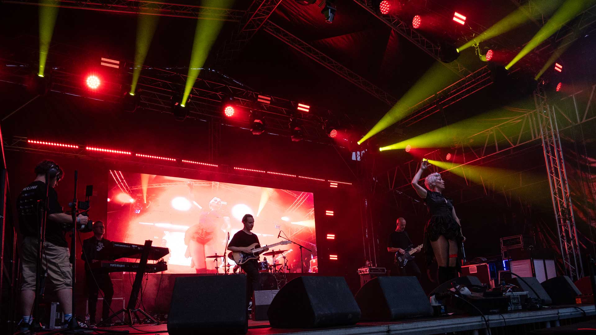 Band performing on a stage lit with red lighting and yellow beams