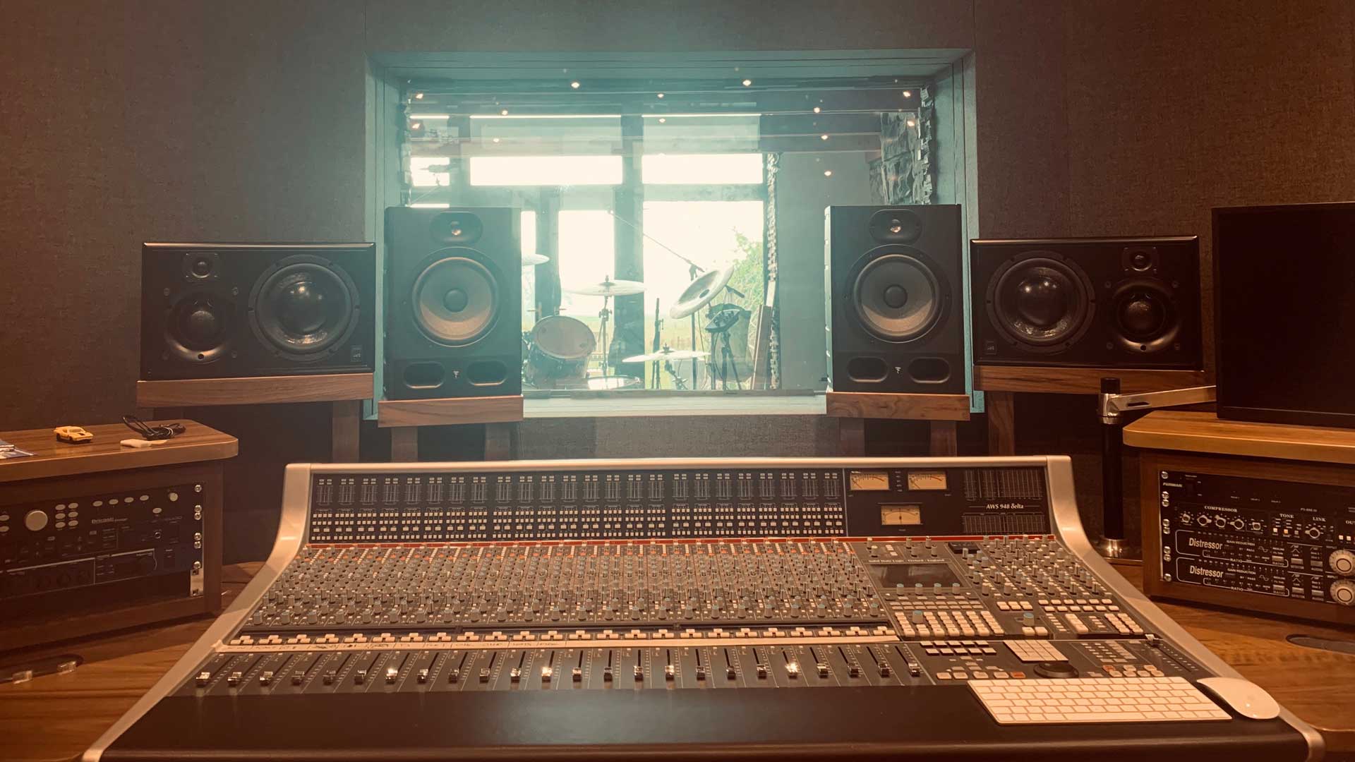 Studio control room with a large mixing console in front of two monitor speakers