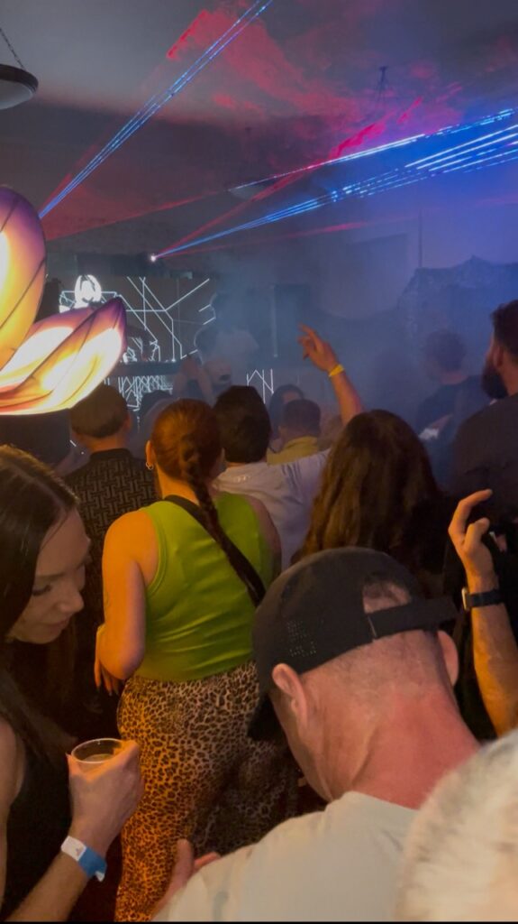 Party guests dancing in the foreground with laser lighting behind them