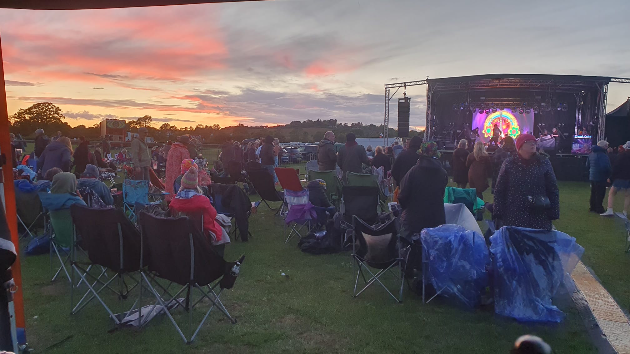 View looking over a crowd seated in front of the stage as the sun sets.
