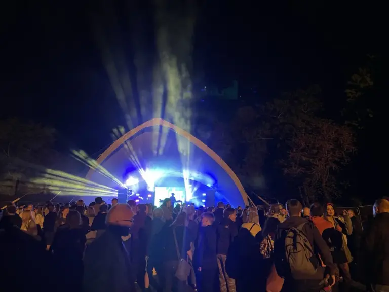 Audience watching a live performance ona stage with lights shinning out.