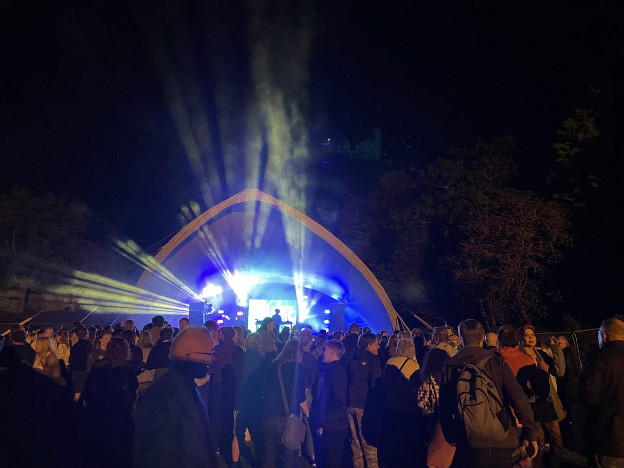 Audience watching a live performance ona stage with lights shinning out.