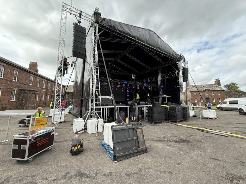 Roofed outdoor stage and equipment cases on site at Carlisle Castle before the show
