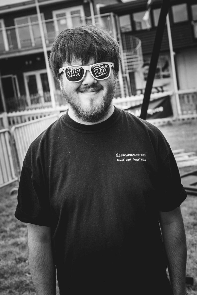 Tom Kamudu in sunglasses and a black t-shirt, in black and white