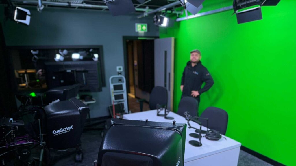 Green screen studio with a technician and a control desk in the foreground