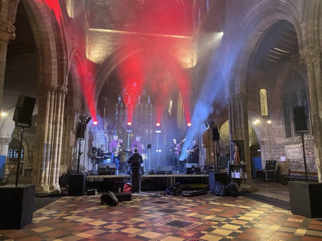 Stage with red and blue lighting set up inside a stone church with arched windows