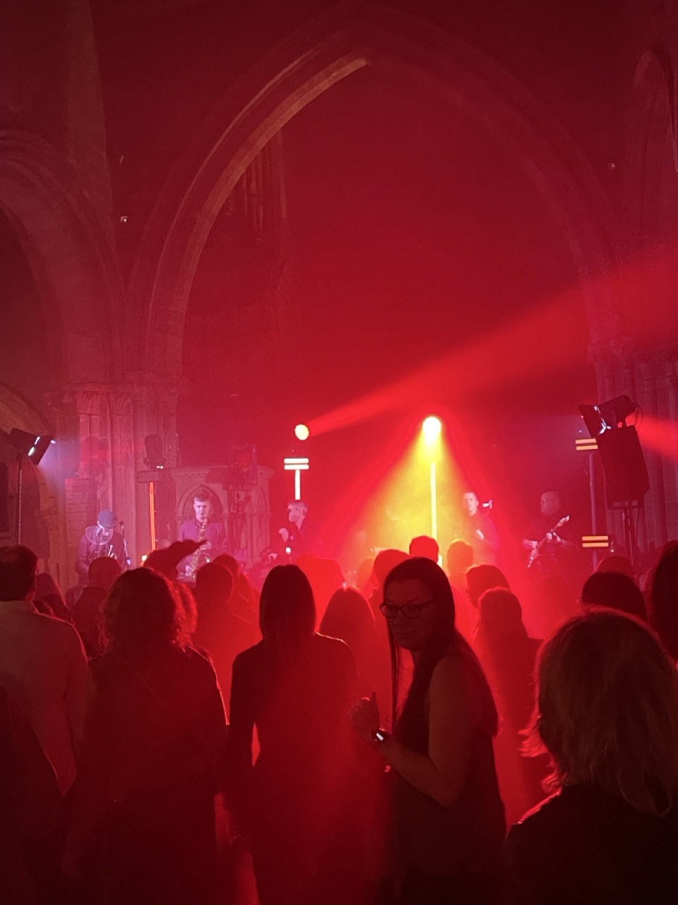 Red lights shine from a stage silhouetting an audience.