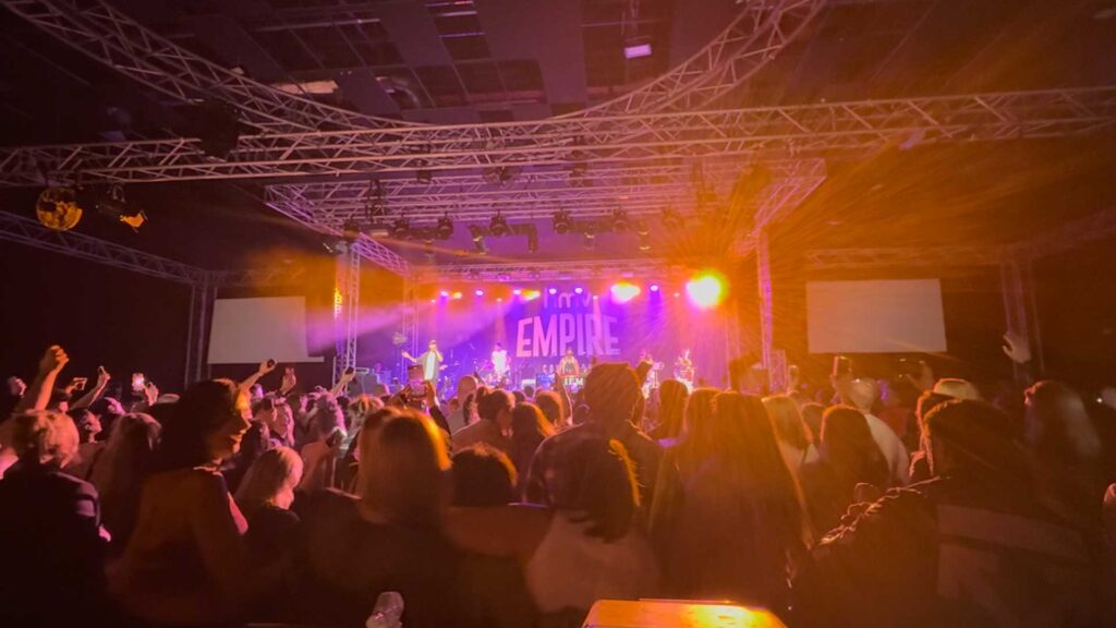 Band on stage lit in orange and purple with the crowd in the foreground