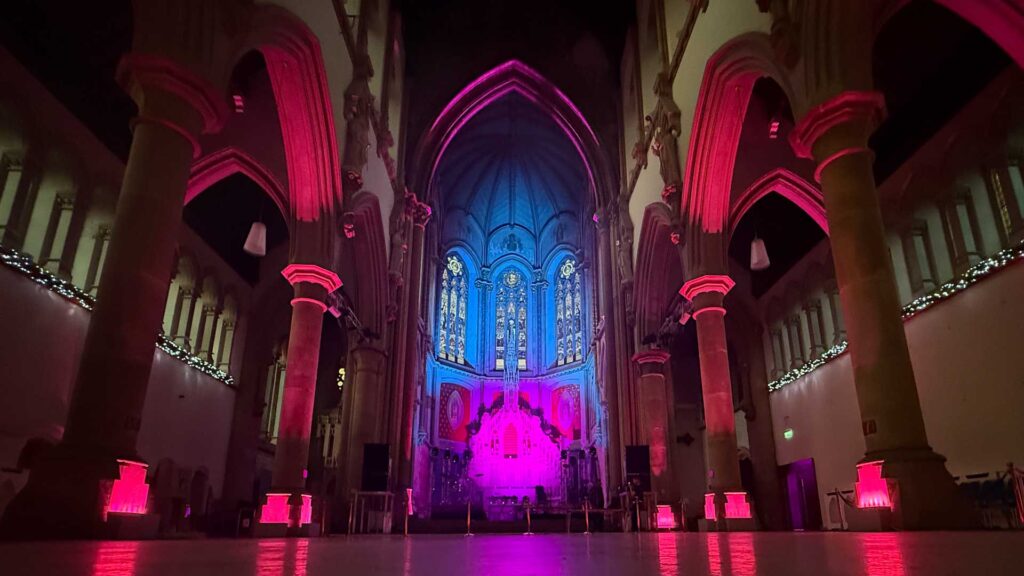 The Monastery church space empty prior to the event opening, pink, blue and red colour hues creating a warm and inviting space.