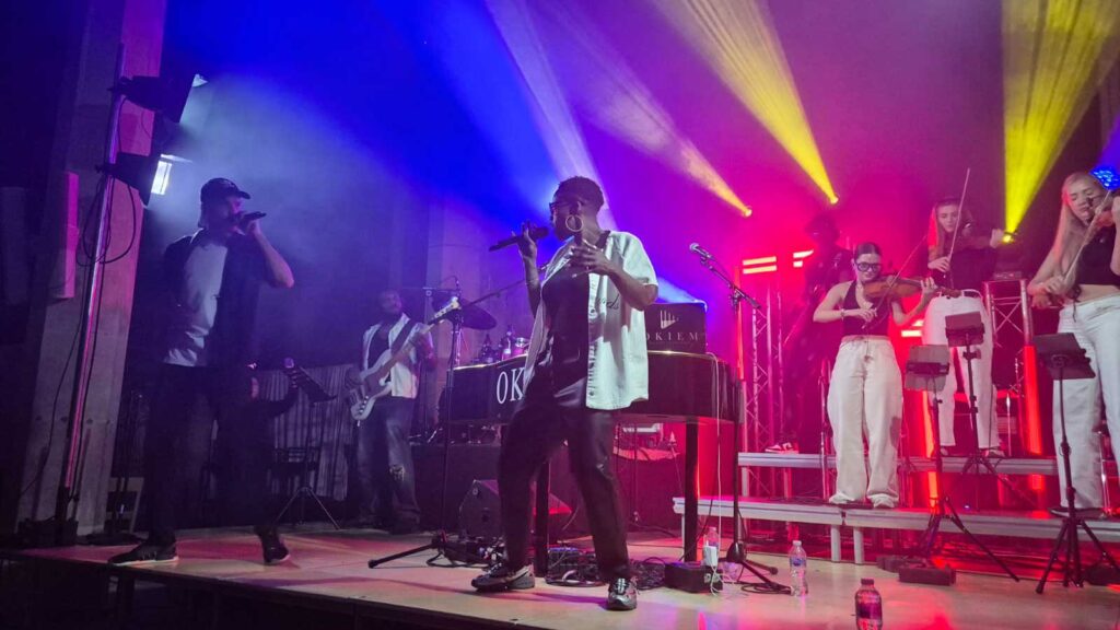 Band with string quartet playing on stage with colourful stage lighting