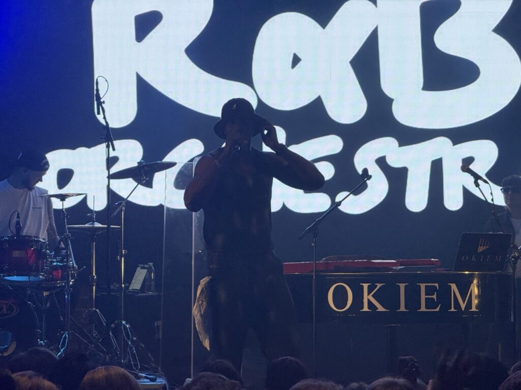 Orchestra logo projected on a screen above a performer in silhouette