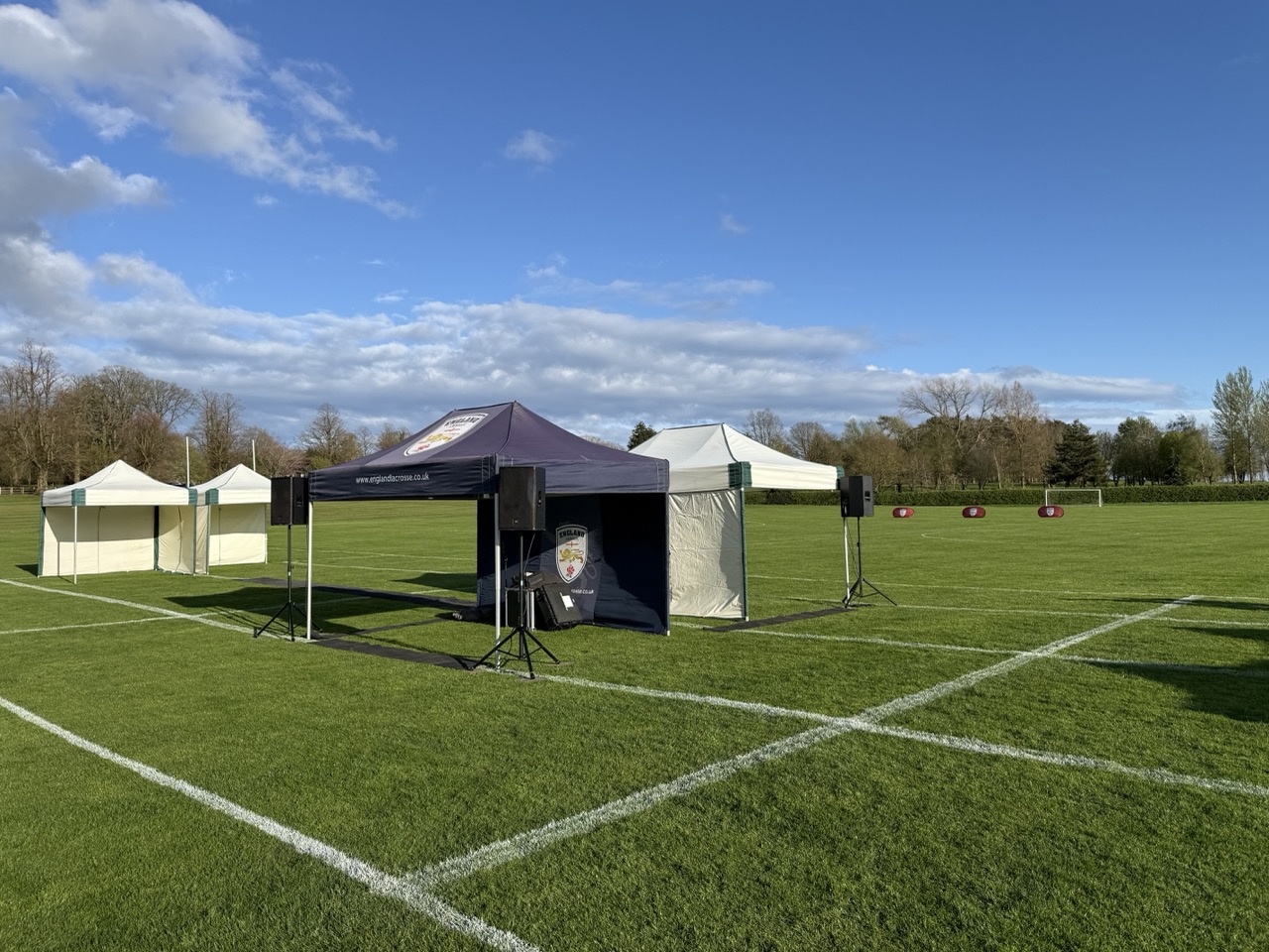 2 gazebos set up in a field with 3 speakers on tripopd stands