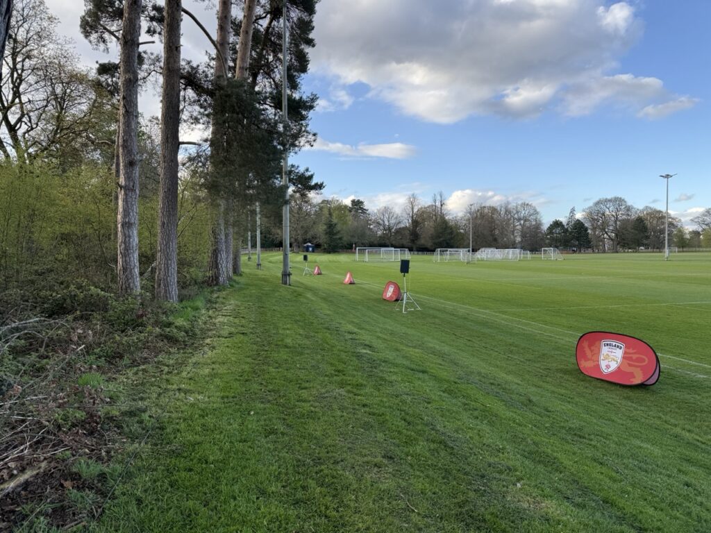 Grass pitch with orange cones and a speaker on a stand