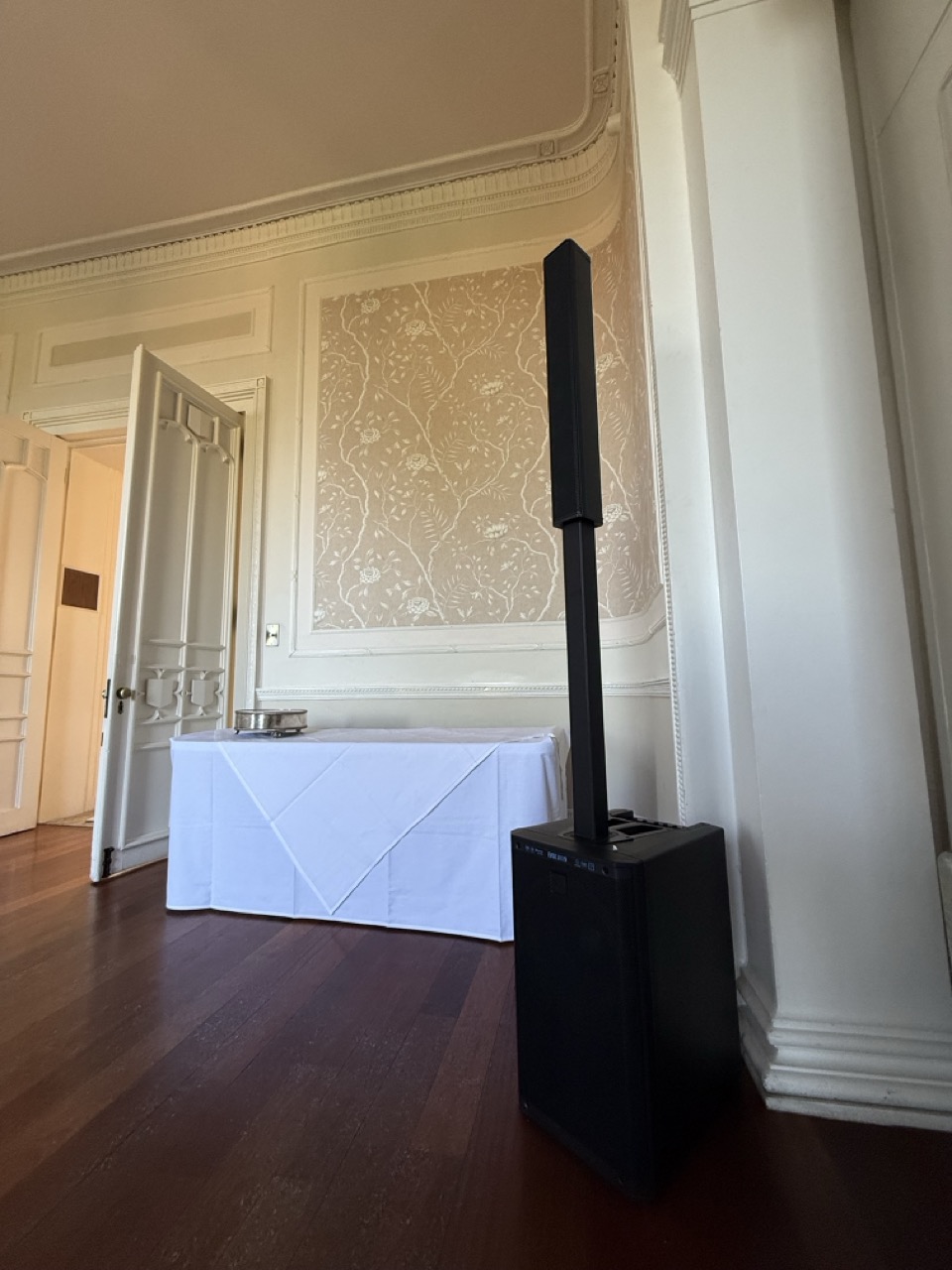 A speaker set up in a room with a table behind it.