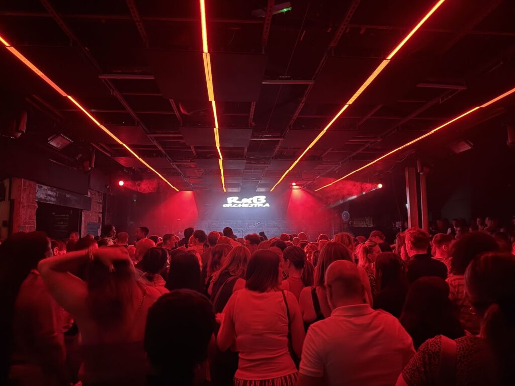 Crowd in red lighting with vertical red beams cutting across the ceiling