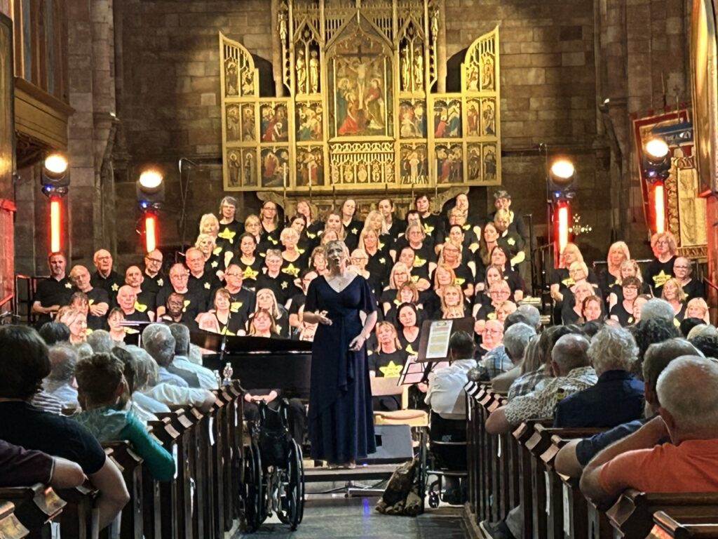 Choir singing in front of an ornate altar with the audience seated in the nave