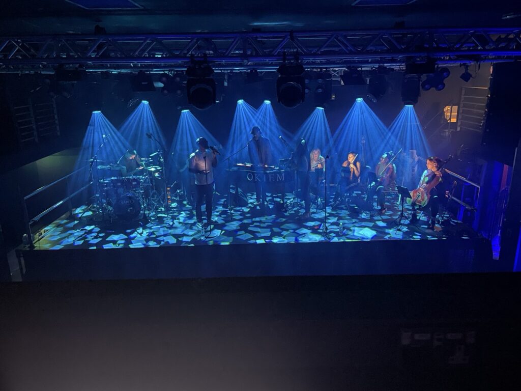 Orchestra performing on a stage lit in blue